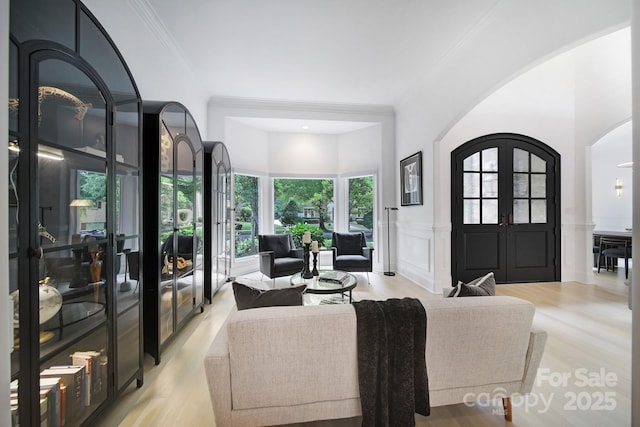 8016 Pemswood St, Charlotte, NC 28277 - living area featuring arched walkways, french doors, wainscoting, a decorative wall, and light wood finished floors