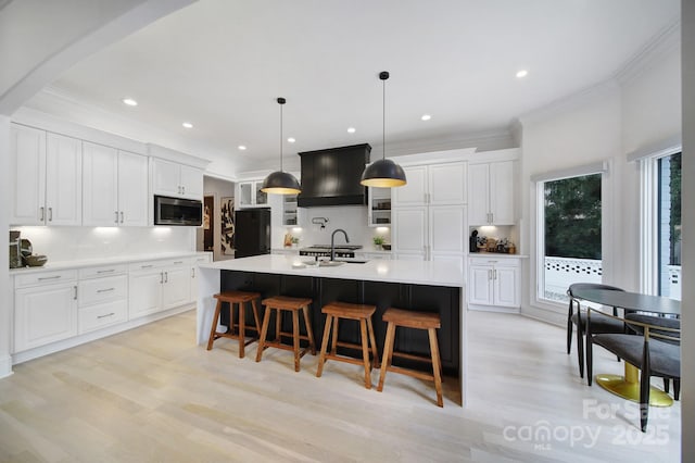 8016 Pemswood St, Charlotte, NC 28277 - kitchen featuring stainless steel microwave, custom exhaust hood, light wood-style floors, a kitchen bar, and white cabinets