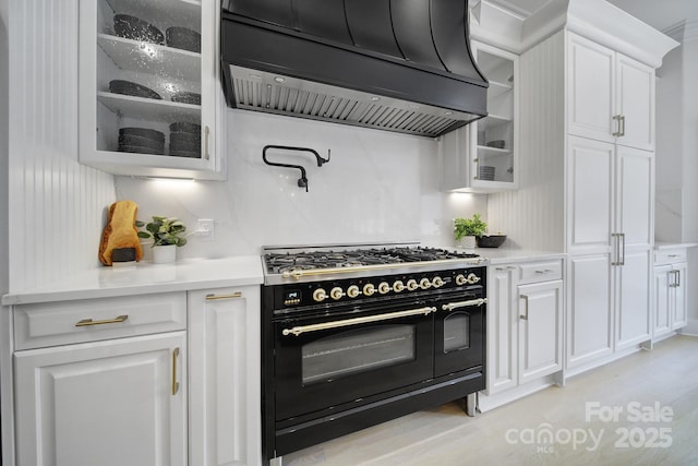 8016 Pemswood St, Charlotte, NC 28277 - kitchen with double oven range, custom range hood, white cabinetry, glass insert cabinets, and light countertops