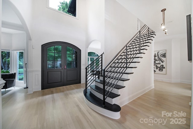 8016 Pemswood St, Charlotte, NC 28277 - foyer entrance with arched walkways, stairs, wood finished floors, a high ceiling, and wainscoting