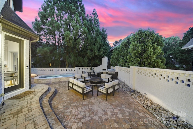8016 Pemswood St, Charlotte, NC 28277 - patio terrace at dusk featuring a patio area, a fenced backyard, an outdoor hot tub, and an outdoor living space with a fire pit