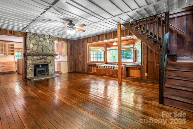 65 Woodfern Dr, Maggie Valley, NC 28751 - unfurnished living room with hardwood / wood-style flooring, a stone fireplace, stairs, wood walls, and ceiling fan
