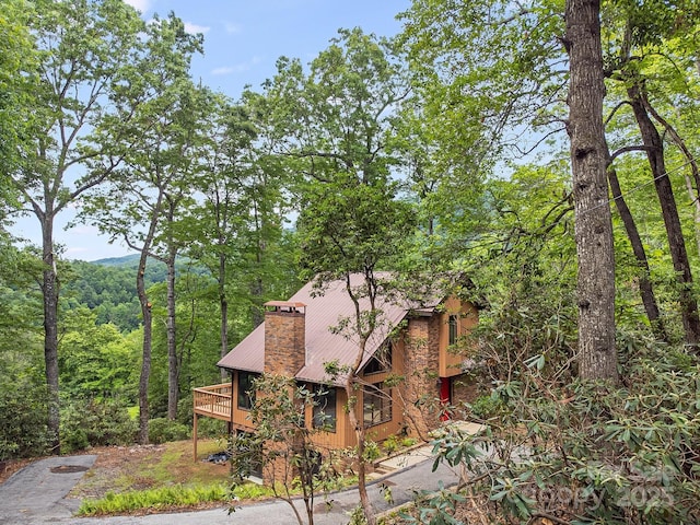 285 Fairway Loop Unit 7, Burnsville, NC 28714 - view of home's exterior featuring a chimney, a metal roof, a forest view, and a deck