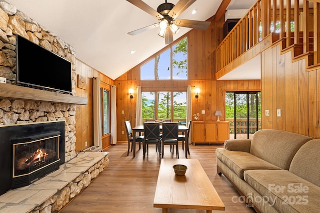 285 Fairway Loop Unit 7, Burnsville, NC 28714 - living area with wood walls, high vaulted ceiling, a stone fireplace, a ceiling fan, and wood finished floors