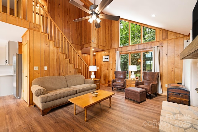 285 Fairway Loop Unit 7, Burnsville, NC 28714 - living room featuring wood walls, healthy amount of natural light, high vaulted ceiling, stairway, and light wood-type flooring