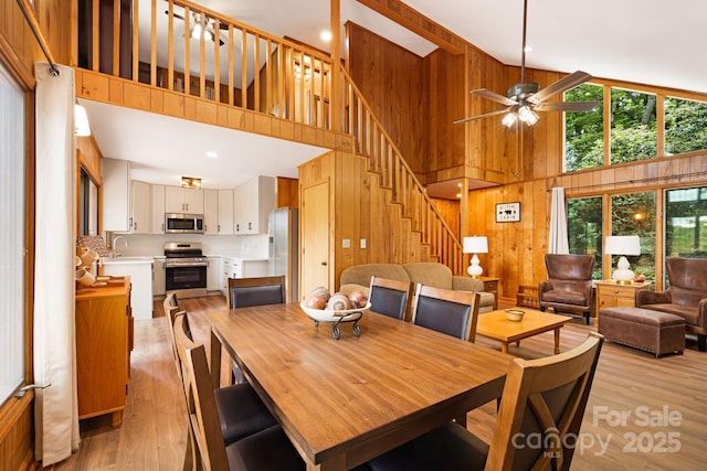 285 Fairway Loop Unit 7, Burnsville, NC 28714 - dining area with a high ceiling, wood walls, stairway, light wood-style flooring, and a ceiling fan