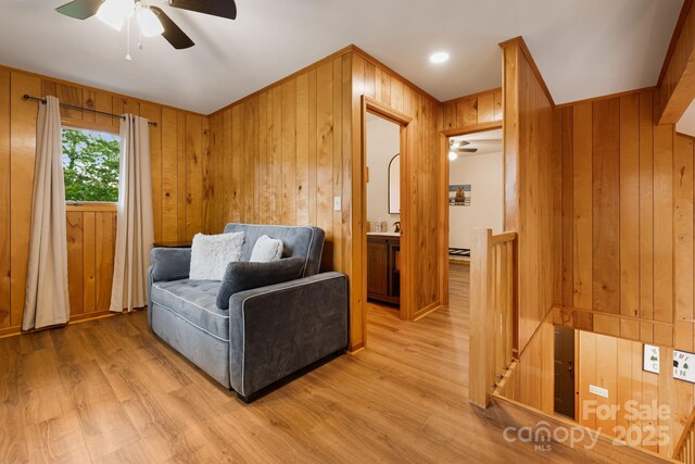 285 Fairway Loop Unit 7, Burnsville, NC 28714 - sitting room featuring an upstairs landing, ceiling fan, wood walls, and light wood-style flooring