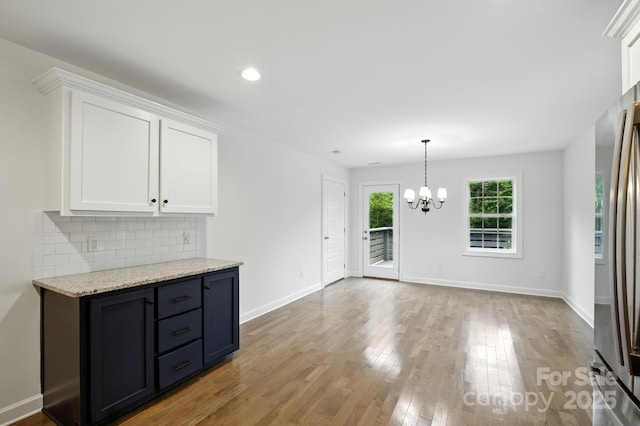 8782 Shepherd Ct, Hildebran, NC 28612 - kitchen featuring a chandelier, white cabinets, wood finished floors, decorative backsplash, and freestanding refrigerator