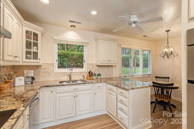 103 Golfside Dr, Flat Rock, NC 28731 - kitchen with a peninsula, decorative backsplash, ceiling fan, glass insert cabinets, and light wood-type flooring