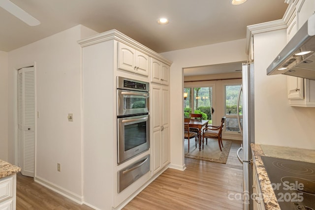 103 Golfside Dr, Flat Rock, NC 28731 - kitchen featuring a warming drawer, wall chimney exhaust hood, stainless steel appliances, light wood finished floors, and light stone countertops