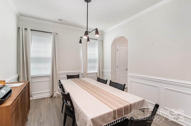 15636 Oleander Dr, Charlotte, NC 28278 - dining area featuring plenty of natural light, ornamental molding, arched walkways, light wood-style floors, and a wainscoted wall