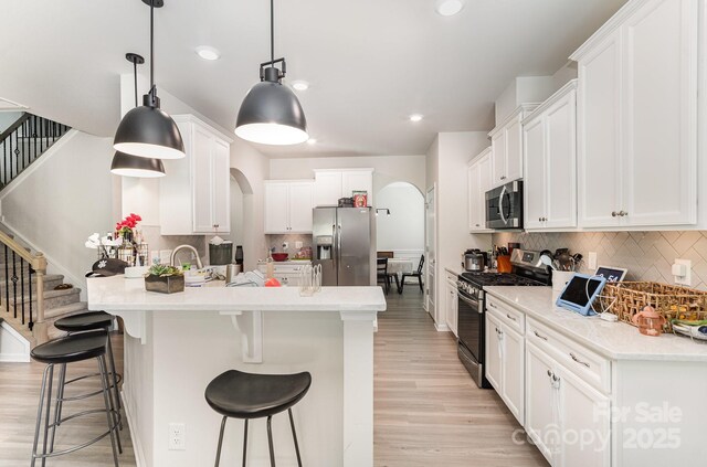 15636 Oleander Dr, Charlotte, NC 28278 - kitchen featuring appliances with stainless steel finishes, arched walkways, tasteful backsplash, a kitchen breakfast bar, and recessed lighting