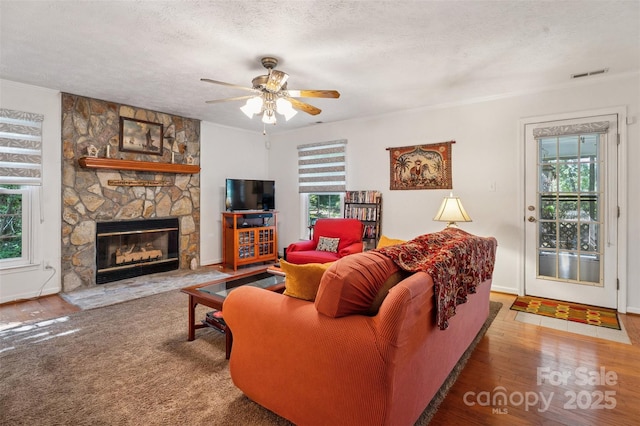 815 La Quinta Ln, Hope Mills, NC 28348 - living room featuring healthy amount of natural light, a fireplace, ceiling fan, wood finished floors, and a textured ceiling