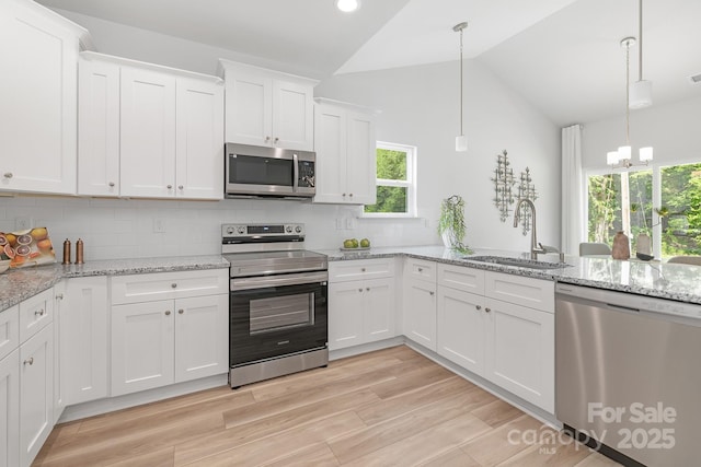 4472 Pebblebrook Cir SW, Concord, NC 28027 - kitchen with stainless steel appliances, vaulted ceiling, white cabinetry, backsplash, and plenty of natural light