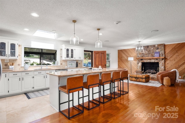 6259 River Cabin Ln, Charlotte, NC 28278 - kitchen with wooden walls, a textured ceiling, a breakfast bar, a center island, and glass insert cabinets