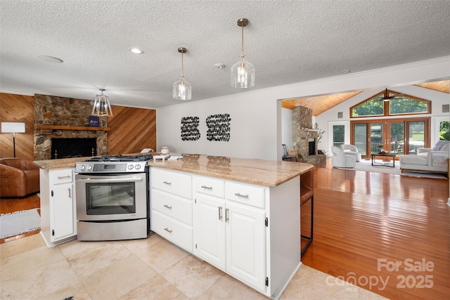 6259 River Cabin Ln, Charlotte, NC 28278 - kitchen with open floor plan, a fireplace, stainless steel gas range, wood walls, and a textured ceiling