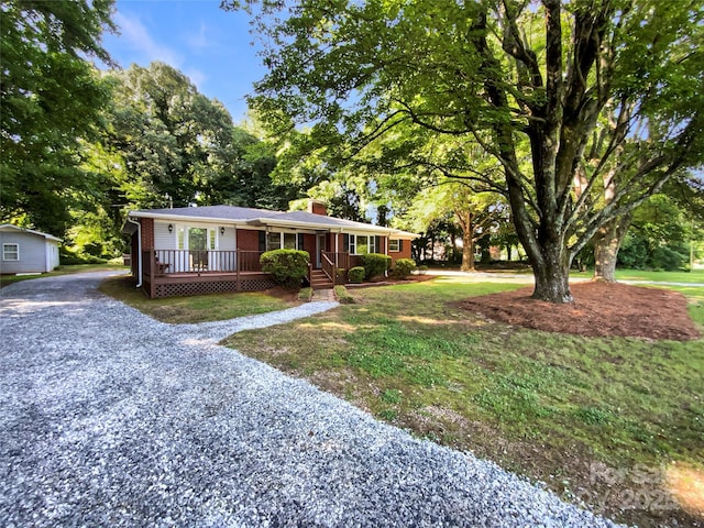 7812 Old Concord Rd, Salisbury, NC 28146 - ranch-style house featuring covered porch, gravel driveway, a chimney, and view of scattered trees