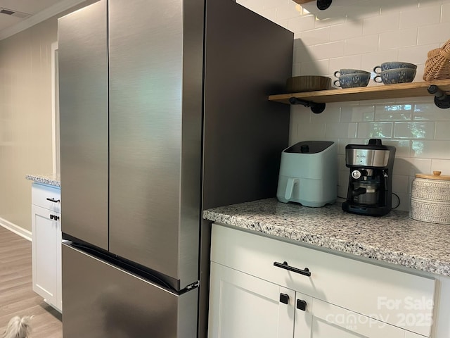 107 Byrd St, Morganton, NC 28655 - kitchen view of freestanding refrigerator, light wood-style floors, white cabinetry, light stone countertops, and open shelves
