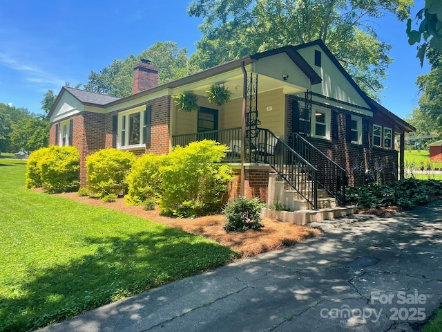 107 Byrd St, Morganton, NC 28655 - ranch-style house with a chimney, brick siding, a front lawn, stairs, and a porch