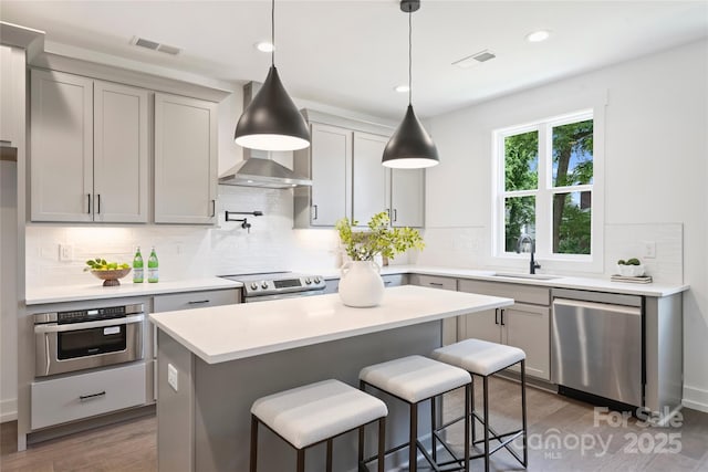 209 Coxe Ave Unit A, Charlotte, NC 28208 - kitchen with appliances with stainless steel finishes, wood finished floors, a kitchen bar, decorative backsplash, and light countertops