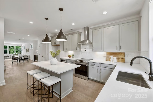 209 Coxe Ave Unit A, Charlotte, NC 28208 - kitchen with wall chimney exhaust hood, electric range, a kitchen breakfast bar, a center island, and tasteful backsplash
