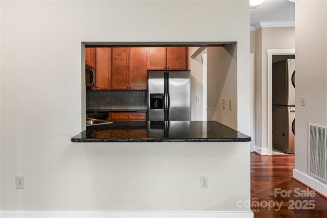9 Kenilworth Knl, Asheville, NC 28805 - kitchen featuring appliances with stainless steel finishes, stacked washer / drying machine, tasteful backsplash, a peninsula, and dark wood-style flooring