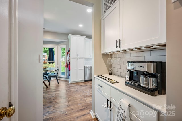 1045 Fairway Ridge Rd NW, Concord, NC 28027 - kitchen with wood finished floors, white cabinetry, backsplash, recessed lighting, and glass insert cabinets