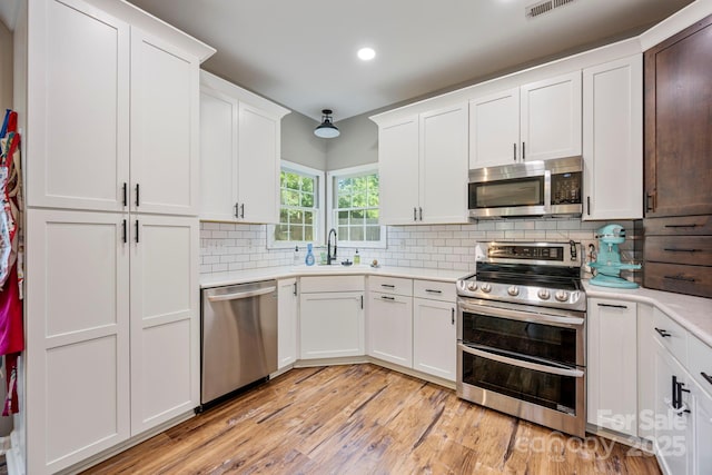1045 Fairway Ridge Rd NW, Concord, NC 28027 - kitchen featuring stainless steel appliances, light countertops, light wood-style floors, tasteful backsplash, and white cabinetry