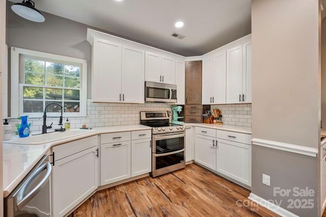 1045 Fairway Ridge Rd NW, Concord, NC 28027 - kitchen featuring appliances with stainless steel finishes, light countertops, white cabinets, backsplash, and recessed lighting