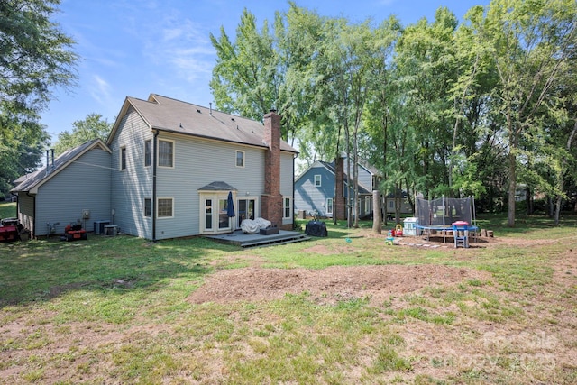 1045 Fairway Ridge Rd NW, Concord, NC 28027 - rear view of property with a trampoline, a wooden deck, a yard, and a chimney