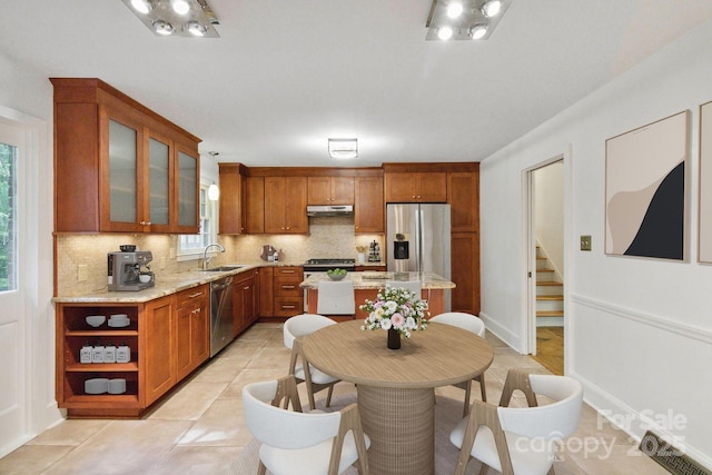 6921 Thermal Rd, Charlotte, NC 28211 - kitchen with stainless steel appliances, under cabinet range hood, tasteful backsplash, brown cabinets, and glass insert cabinets