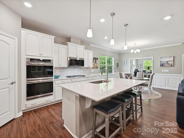 15614 Aviary Orchard Way, Charlotte, NC 28278 - kitchen featuring stainless steel appliances, a chandelier, white cabinetry, a kitchen bar, and crown molding