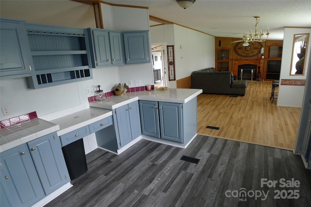 236 Boxwood Church Rd, Mocksville, NC 27028 - kitchen featuring blue cabinets, dark wood finished floors, open floor plan, a peninsula, and a chandelier