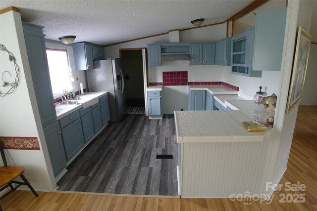 236 Boxwood Church Rd, Mocksville, NC 27028 - kitchen featuring blue cabinetry, stainless steel fridge with ice dispenser, a peninsula, dark wood-style floors, and vaulted ceiling