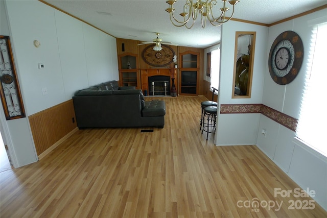 236 Boxwood Church Rd, Mocksville, NC 27028 - living area with a ceiling fan, light wood-style flooring, a fireplace with raised hearth, a chandelier, and crown molding