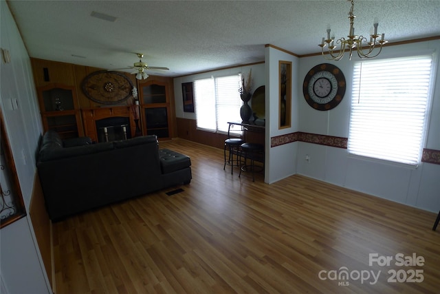 236 Boxwood Church Rd, Mocksville, NC 27028 - living room featuring a chandelier, wood finished floors, ceiling fan, a textured ceiling, and a glass covered fireplace