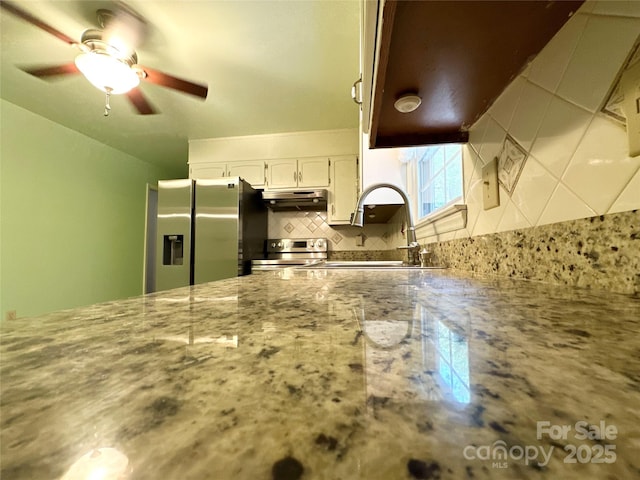 1164 Hidden Lake Dr Unit 10, Granite Falls, NC 28630 - kitchen featuring under cabinet range hood, appliances with stainless steel finishes, tasteful backsplash, white cabinetry, and light stone countertops