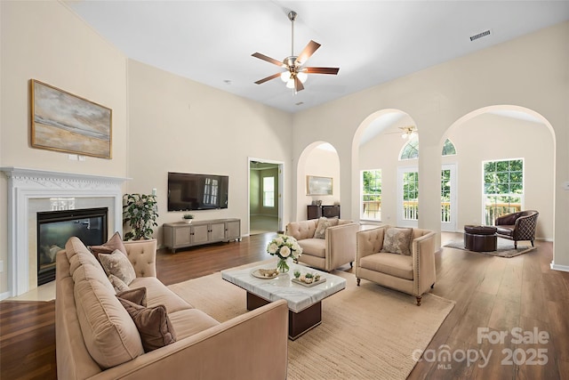 14103 Hiawatha Ct, Huntersville, NC 28078 - living room with ceiling fan, wood finished floors, arched walkways, a high end fireplace, and a high ceiling