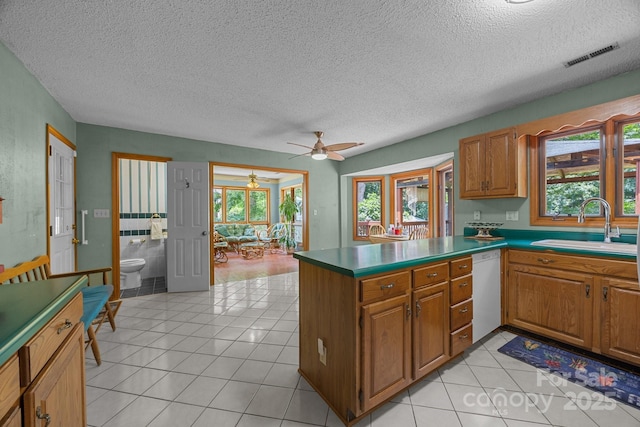 324 Swamp Fox Dr, Fort Mill, SC 29715 - kitchen with dishwasher, a textured ceiling, a peninsula, plenty of natural light, and brown cabinets