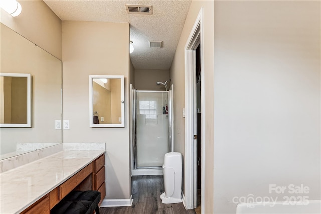 2040 Brantley Creek Dr, Kannapolis, NC 28083 - bathroom featuring a textured ceiling, wood finished floors, vanity, and a stall shower