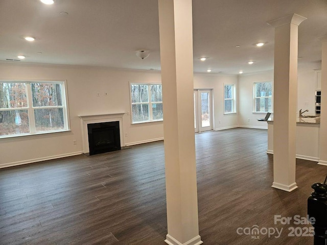 8231 Annsborough Dr NW, Concord, NC 28027 - unfurnished living room featuring ornamental molding, a fireplace with flush hearth, plenty of natural light, dark wood-style floors, and recessed lighting
