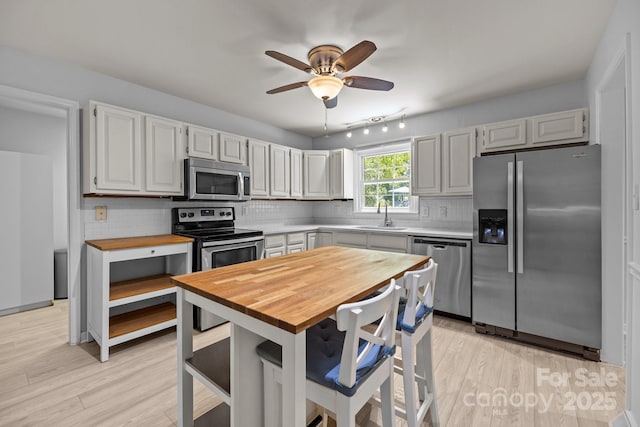 11329 Torino Rd, Matthews, NC 28105 - kitchen featuring appliances with stainless steel finishes, tasteful backsplash, ceiling fan, light wood finished floors, and butcher block counters