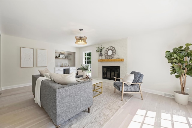 811 Ashmeade Rd, Charlotte, NC 28211 - living area featuring light wood-style flooring, a brick fireplace, wine cooler, and a bar