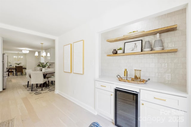 811 Ashmeade Rd, Charlotte, NC 28211 - indoor bar with beverage cooler, decorative backsplash, light wood-type flooring, freestanding refrigerator, and a chandelier
