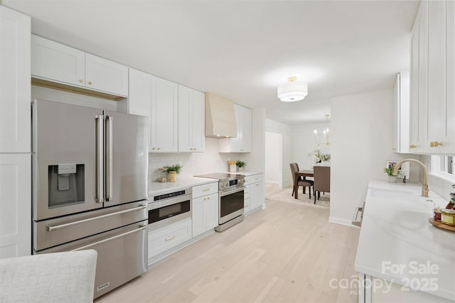 811 Ashmeade Rd, Charlotte, NC 28211 - kitchen with appliances with stainless steel finishes, custom exhaust hood, light wood-style floors, white cabinets, and tasteful backsplash