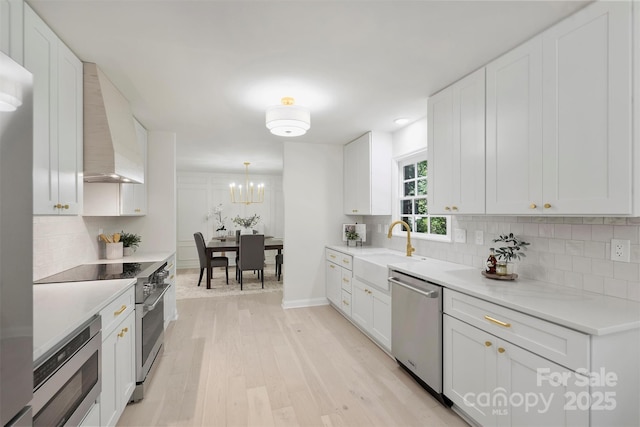 811 Ashmeade Rd, Charlotte, NC 28211 - kitchen featuring stainless steel appliances, wall chimney exhaust hood, light wood finished floors, backsplash, and white cabinetry