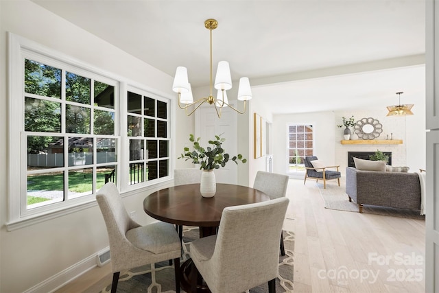811 Ashmeade Rd, Charlotte, NC 28211 - dining space featuring light wood-type flooring, a chandelier, and a fireplace