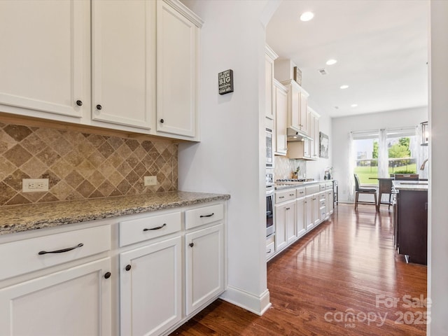 1009 Hampton Grove Rd, Waxhaw, NC 28173 - kitchen with dark wood finished floors, arched walkways, white cabinetry, decorative backsplash, and stainless steel appliances