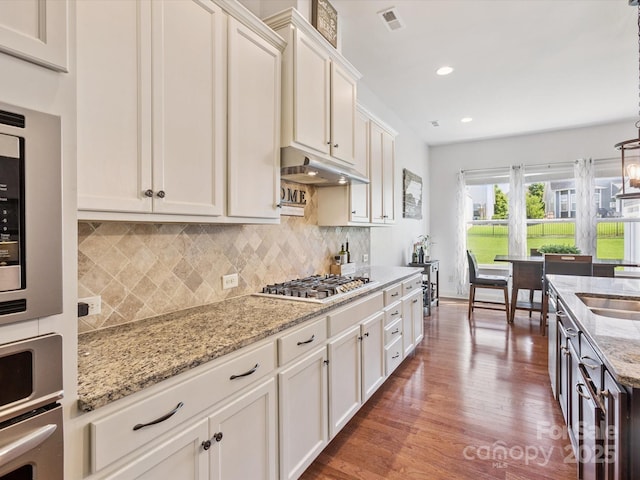 1009 Hampton Grove Rd, Waxhaw, NC 28173 - kitchen featuring stainless steel appliances, under cabinet range hood, wood finished floors, light stone counters, and backsplash