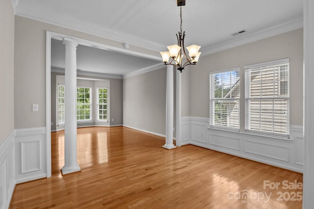 4519 Rock Stream Dr, Charlotte, NC 28269 - spare room featuring light wood-style floors, ornamental molding, a chandelier, a wainscoted wall, and ornate columns